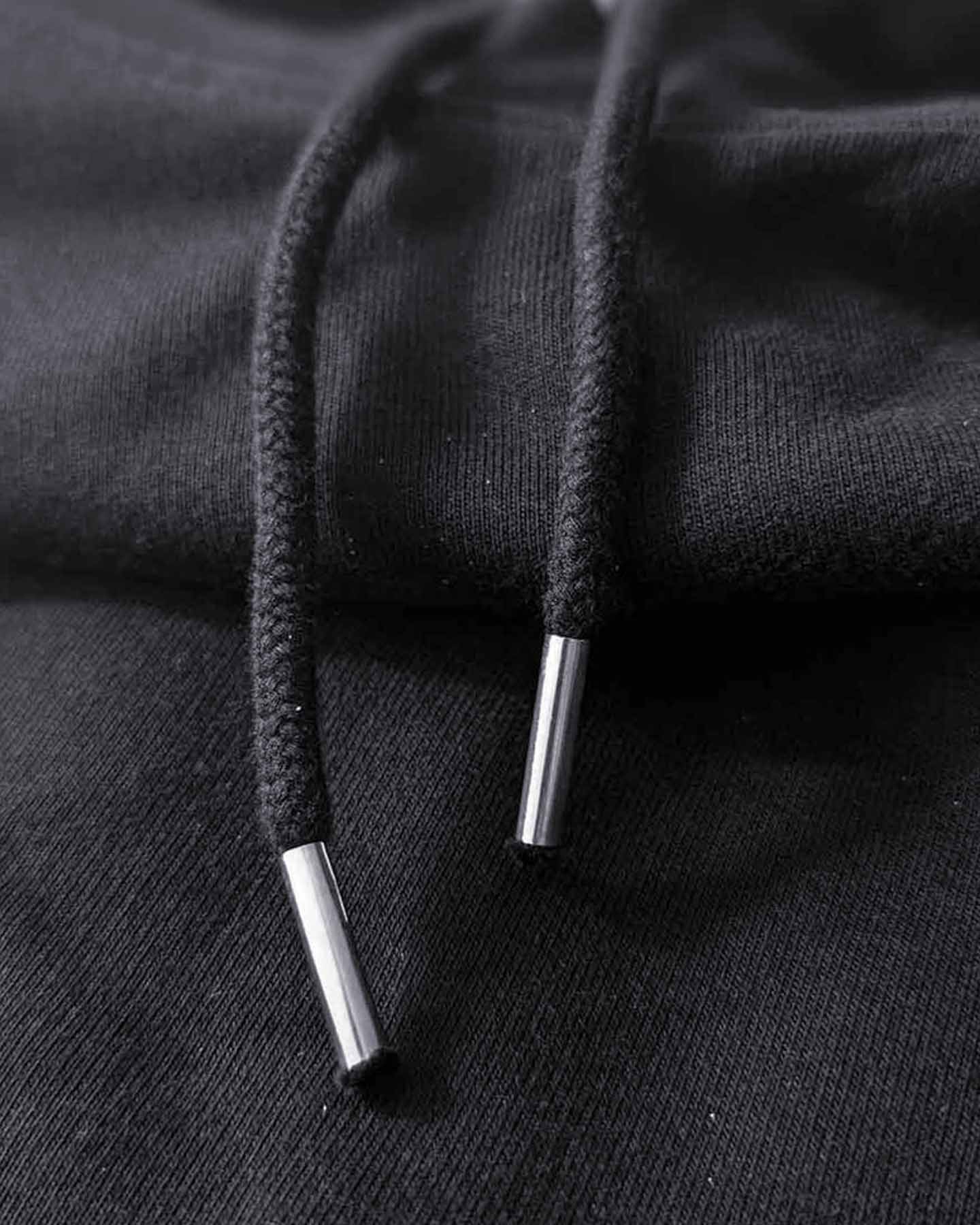 Macro shot of a black hoodie's drawstrings showing the detail and the quality